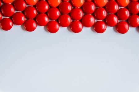 red sweet candy dragees on isolated white background. Decorative Creative composition of round candy dragees in Rainbow colors. Concept Summer. Top view. Flat lay.の写真素材