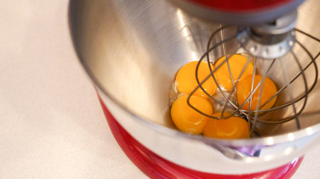 Raw eggs in a metal bowl of standing mixer. Preparing egg yolk with sugar in kitchen mixer.の写真素材