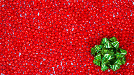 Boxing Day concept with space for text decorated with sparkling green bow against red color peppermint heart shaped candies backgroundの写真素材