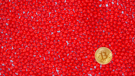 Golden Bitcoin coin on a red heart shaped candy background. Bitcoin cryptocurrency value price fall...