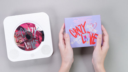 Fan hands holding 1st music album of k-pop group Itzy CRAZY IN LOVE on grey background. Pink music...
