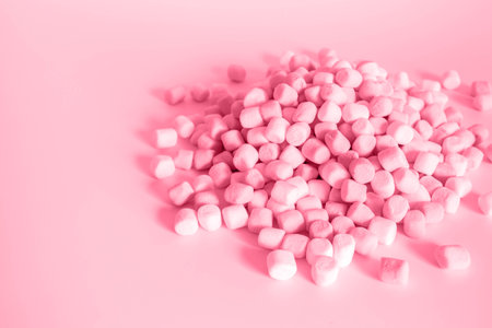Color of year 2023 Viva Magenta. Image with small round marshmallows is toned in color of viva magenta. New Fashion colour. Pile of twisted marshmallows. Side view. Sweetsの写真素材