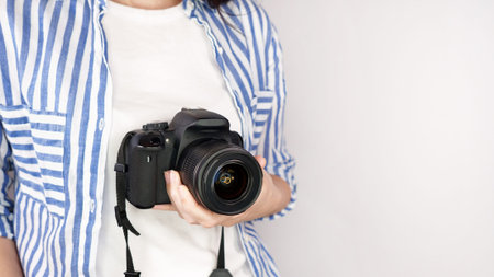 Photographer holding dslr camera. Self portrait, front view. Faceless nice woman with brown red hair...