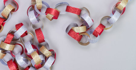 Colorful background with strips of gold silver red sparkling chain garland on grey. Festive Christmas birthday decoration garland.Space for textの写真素材