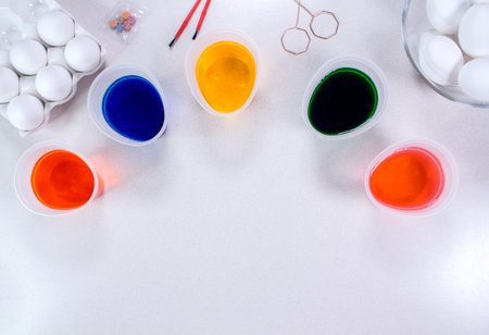 Tools for painting eggs for easter, eggs box, cups of colorful paint, easter eggs, plate, brushes and paints on the table side view.の写真素材