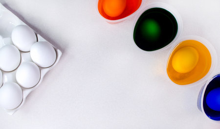 Tools for painting eggs for easter, eggs box, cups of colorful paint, easter eggs, plate, brushes and paints on the table side view.の写真素材