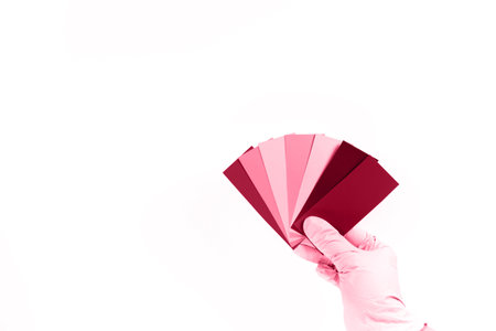 Hand holds a rainbow color palette of paints on a white background. Image tonned in Viva Magenta color of year 2023の写真素材