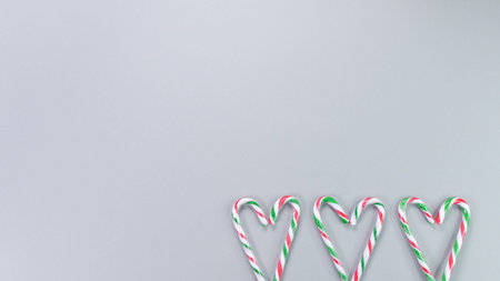 Red, green and white candy canes in the shape of heart on grey background. Valentine's Day concept....