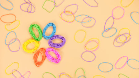 Colored rubber band flower shape on bright yellow paper background. Abstract background. Stationery accessoriesの写真素材