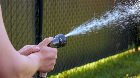 Hose watering plants in the garden by the farmer. Watering with gun nozzle. Shallow depth of field.の写真素材