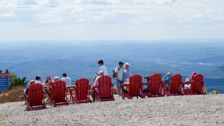 Sightseeing mountain views at Mont Tremblant ski Resort in summer. Tourists enjoying sitting at red chairs at ski resort village. Mont-Tremblant, Quebec, Canada - 22.09.2022のeditorial素材