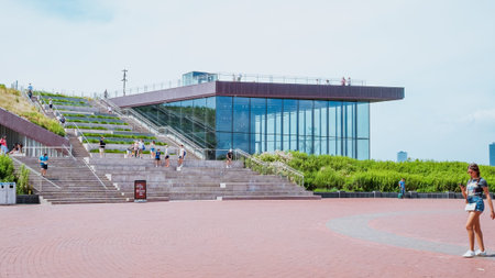 Modern glass and steel Statue of Liberty museum with green roof and city view.