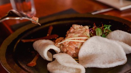 Indulge in a vibrant plate of fresh salmon tartare, artfully seasoned with herbs and spices, elegantly presented with crispy wonton chips, garnished with microgreens for a delightful appetizer.の写真素材