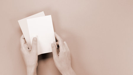 mockup envelop with empty space for text and design in hand of woman on brown background. greeting card, layout for a sloganの写真素材