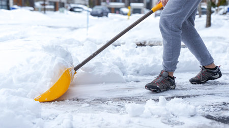 Man shoveling snow off of his driveway after a winter storm in Canada. Man with snow shovel cleans sidewalks in winter. Winter timeの写真素材