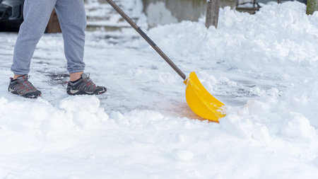 Man shoveling snow off of his driveway after a winter storm. Man with snow shovel cleans sidewalks in winter. Winter timeの写真素材