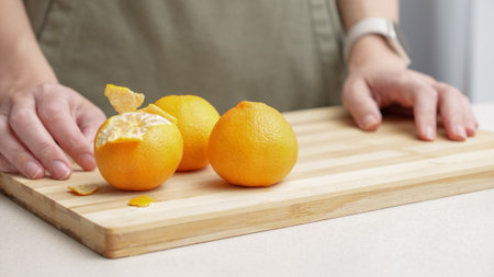 Hands peeling of orange tangerines on the cutting board on table, lots of juicy fresh fruits for cooking on Christmas.の写真素材