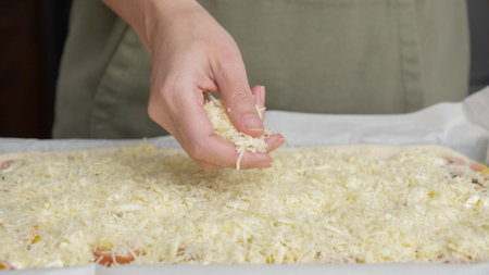 Grated cheese falls out of the cook's hand on pizza. Homemade pizza. Grated cheese for pizzaの写真素材