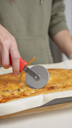 Cutting pizza with a round cutter knife. Close-up of delicious pizza being cut into pieces. Slow motion slicing a pizza into multiple slices with a cutterの写真素材