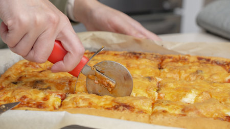 Cutting pizza with a round cutter knife. Close-up of delicious pizza being cut into pieces. Slow motion slicing a pizza into multiple slices with a cutterの写真素材