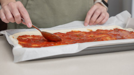 Close Up spreading Tomato Sauce on Pizza Dough. Cooking traditional Sauce for homemade Pizza. Italian Food. Pizza's Makingの写真素材