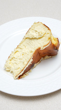 Close-up of a slice of cheesecake with caramel crust on a white plateの写真素材