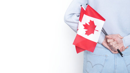 Unrecognized girl student in white blue shirt holding small Canadian flag over gray background, Canada day, holiday, vote, immigration, copy space.の写真素材