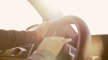 A man confidently driving a sleek car under a bright blue sky on a sunny dayの写真素材