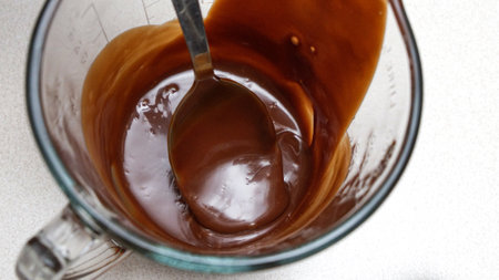 Close-up of a chocolate fudge in a glass measuring cup with a spoon.の写真素材