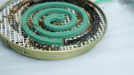 Burning green spiral mosquito repellent coil and red fire with white smoke on dark backgroundの写真素材