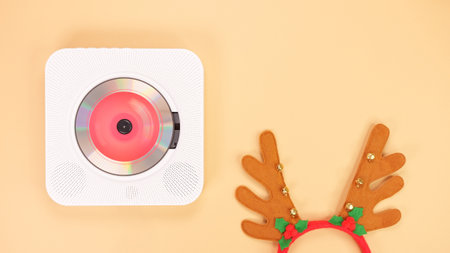 The image shows a white portable CD player with red headphones on a beige background. The CD player has a red light on the front, and the headphones are resting on the right side of the CD player.の写真素材