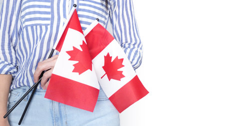 Unrecognized girl student in white blue shirt holding small Canadian flag over gray background, Canada day, holiday, vote, immigration, copy space.の写真素材