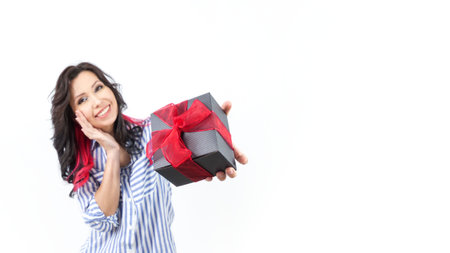 A cheerful woman looks at the camera with a warm smile, wearing a trendy casual outfit. Her long, dark hair enhances the soft, neutral background, creating a joyful and inviting atmosphere.の写真素材