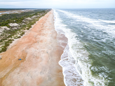 The beach features soft sand that meets clear waters. Gentle waves lap at the shore, creating a tranquil atmosphere perfect for relaxation and enjoyment.の写真素材