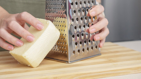 chef grating traditional parmesan cheese with steel grater on the wooden board.の写真素材