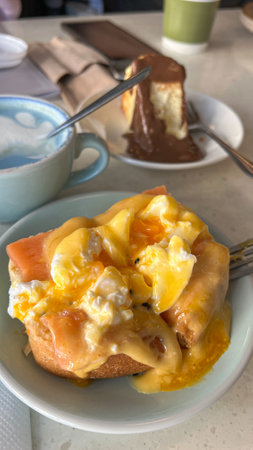 A beautifully plated Eggs Benedict with poached eggs, smoked salmon, and rich hollandaise sauce. Served with a decadent chocolate cheesecake, perfect for brunch or dessert lovers.の写真素材