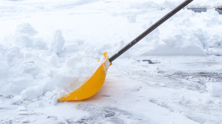 Man shoveling snow off of his driveway after a winter storm in Canada. Man with snow shovel cleans sidewalks in winter. Winter timeの写真素材
