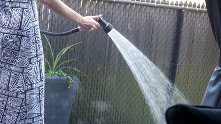 A woman is watering her garden, embodying tranquility and nurturing nature. This scene captures the beauty of growth and care in a personal backyard oasis, highlighting the joy of gardening.の写真素材