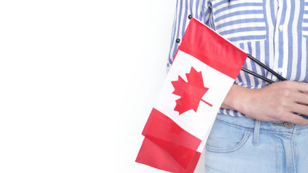 Unrecognized girl student in white blue shirt holding small Canadian flag over gray background, Canada day, holiday, vote, immigration, tax, copy space.の写真素材