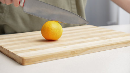 Hands cutting orange tangerines on the cutting board on table, lots of juicy fresh fruits for cooking.の写真素材