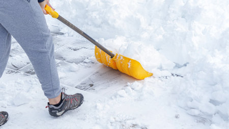 Man shoveling snow off of his driveway after a winter storm in Canada. Man with snow shovel cleans sidewalks in winter. Winter timeの写真素材