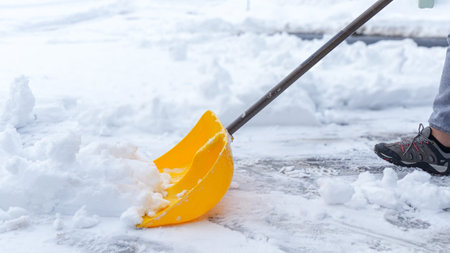 Man shoveling snow off of his driveway after a winter storm in Canada. Man with snow shovel cleans sidewalks in winter. Winter timeの写真素材