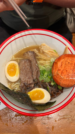 A delicious bowl of ramen featuring a soft-boiled egg, tender beef, and crispy seaweed, offering a comforting and flavorful experience that embodies traditional Japanese cuisine.の写真素材