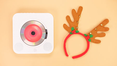 The image shows a white portable CD player with red headphones on a beige background. The CD player has a red light on the front, and the headphones are resting on the right side of the CD player.の写真素材