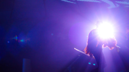 Dramatic lighting highlights a performer captivating the audience with a powerful presence,...