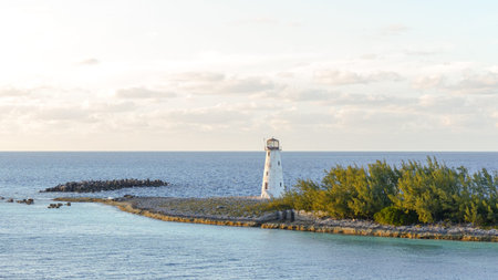 Tall lighthouse on rocky coastline, surrounded by serene waters and vibrant greenery, creating a...