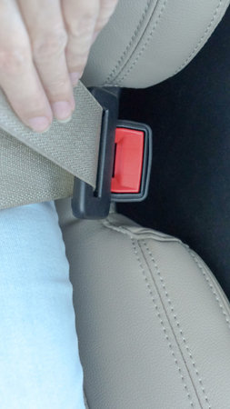 Close-up view of hand securing seatbelt in a contemporary vehicle, showcasing safety mechanisms and...