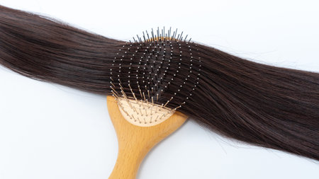 Hair extensions are elegantly arranged on a wooden brush, highlighting their glossy texture and...