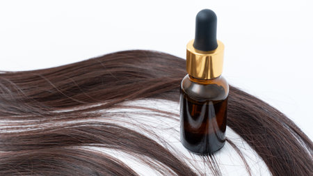 Hair treatment oil bottle positioned next to sleek hair strands, highlighting the benefits of nourishing formulas for split ends and overall hair healthの写真素材