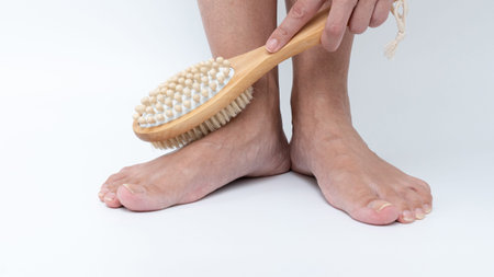 Tired legs and feet are being brushed with a wooden body brush, emphasizing self-care and relaxation...